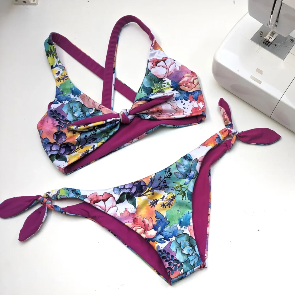 Jak ušít plavky: Barevné plavky šité doma ležící vedle bílého šicího stroje.